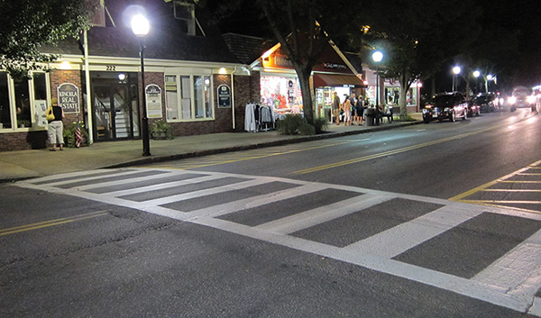 Figure 36. An image showing a ladder-style crosswalk on a two-lane street with on-street parking lanes in a shopping district at night.