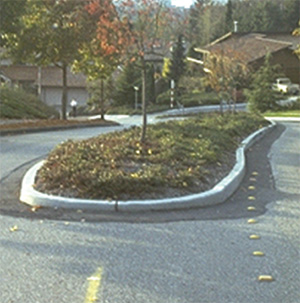Figure 7 (top). Two pictures showing curb treatments. The picture on top shows a vertical curb around a median island; the picture on the bottom shows a sloping curb around a median island.
