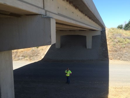 "The elevation of the prestressed concrete multigirder bridge is shown. A construction worker is standing under the bridge in the roadway."