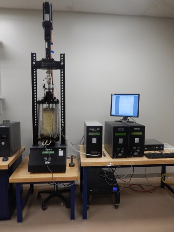 Figure 4. This image shows the resilient modulus device in the lab, with a computer monitor and other equipment on the desk nearby.