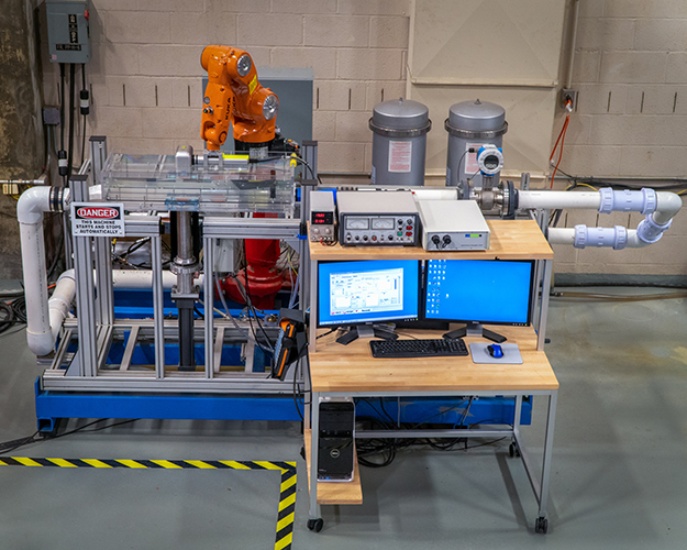 "the ex-situ scour testing device, including the rectangular flow channel, the soil sample and hydraulic piston, the industrial robot arm with laser scanner, and computer control system."