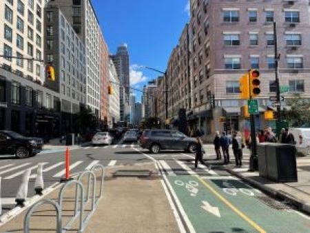 Busy urban intersection showing vehicles, pedestrians, bike lanes, crosswalks, traffic lights, bollards, and other safety countermeasures 