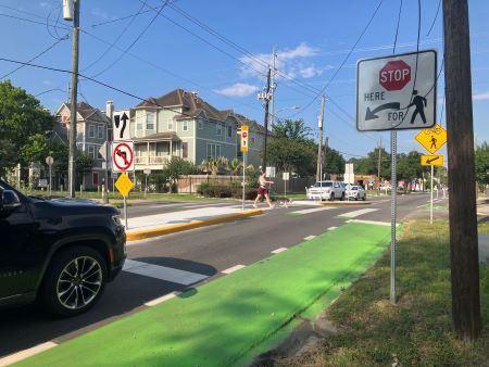 Stopped cars near a cross walk while a pedestrian and an animal are crossing the street