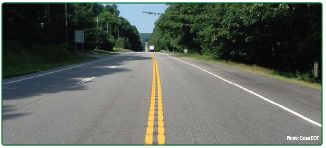 "A long, straight, tree-lined rural roadway featuring center line rumble strips."