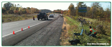 "Workers conducting field noise measurement on a rural roadway."