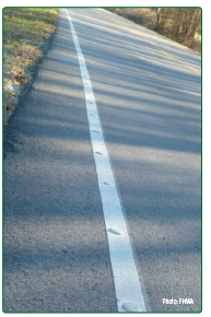 "A white edge line with evenly spaced raised pavement markers, also called Botts' dots."