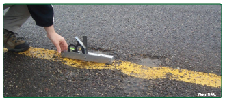 "A man measuring the dimensions of a milled rumble strip."