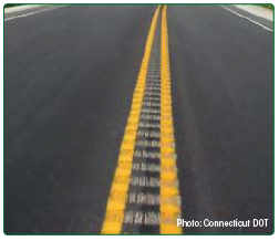 "Photo of center line rumble strips placed over the center line marking on a two-lane roadway. Photo: Connecticut DOT"