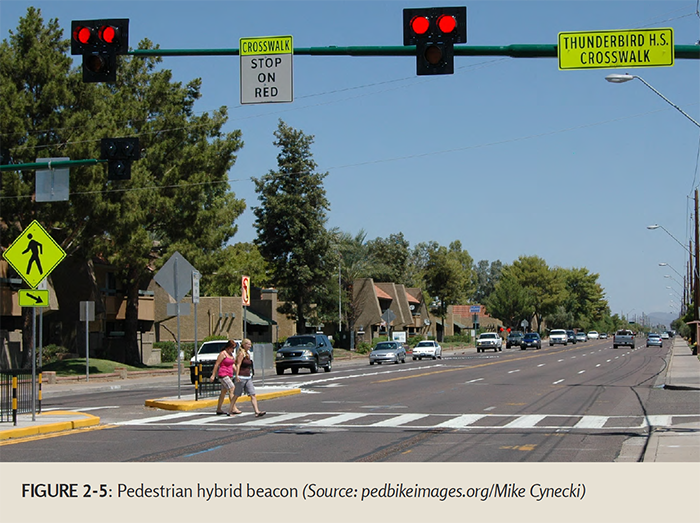 "FIGURE 2-5: Pedestrian hybrid beacon (Source: pedbikeimages.org/Mike Cynecki) - Two women crossing a multi-lane road at a crosswalk"