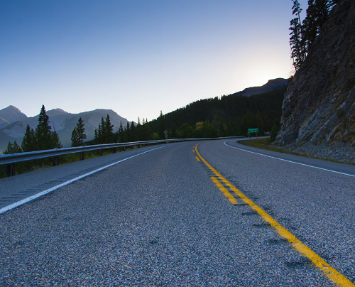 "two lane road in the mountains curving to the right"