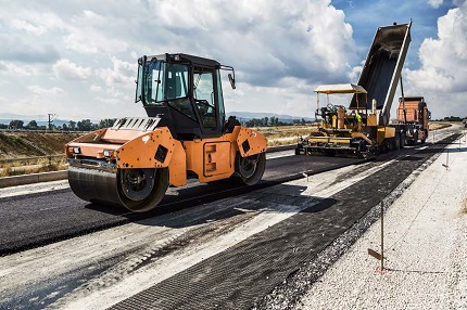 "road crew using heavy equipment to pave a road"