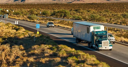 "a semi-trailer truck on a rural highway"