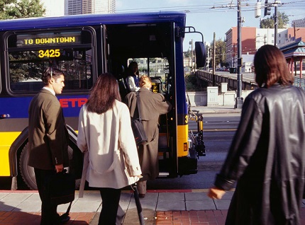 "people getting on a transit bus at an urban street corner"