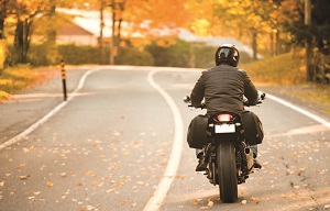 "a motorcyclist riding on a suburban street"