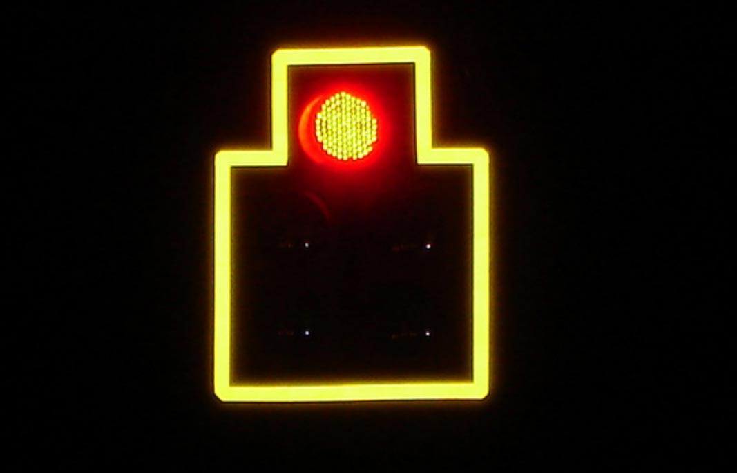 "A traffic signal showing RED. A yellow retroreflective border is visible, outlining the border of the signal."