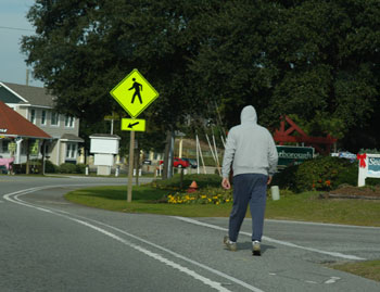 "Photo.  A pedestrian walking with the flow of traffic along the shared use shoulder."