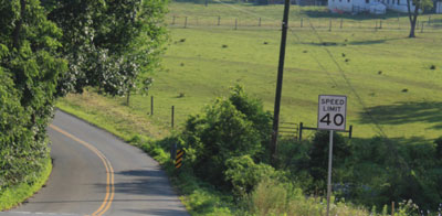 "Photo.  A rural two-lane road with no shoulder."