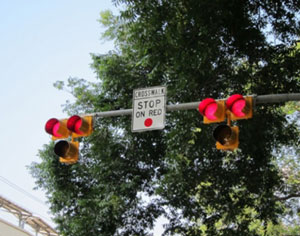 "Photo.  A pedestrian hybrid beacon.  The device consists of three signal sections, with a yellow signal head centered below two horizontally aligned red signal heads.  "