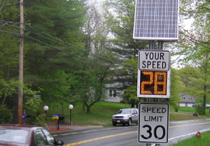 "Photo. A solar-powered speed feedback sign. The bottom part of the sign is a typical speed limit sign with a speed limit of 30 MPH. Above that is a changeable display that states 'Your speed 28 MPH' The speed changed based on how fast a vehicle is traveling. Above that is a solar panel to power the sign."