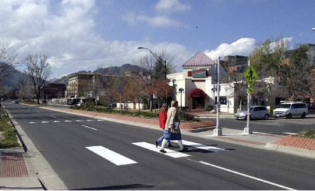 "Photo. A crosswalk with a island or median in the center providing a refuge for pedestrians and a shorter distance to cross."