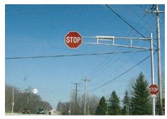 "Photo of an oversize Stop sign mounted to an overhead gantry."