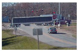 "Photo of a rural stop-controlled intersection with flashing red lights strung over the intersection on the stop approach."