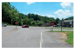 "Photo of a stop-controlled rural intersection where the opposite lanes on the stop approach are separated by a splitter island."