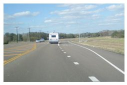 "Photo of a rural roadway with both left and right turn lanes."