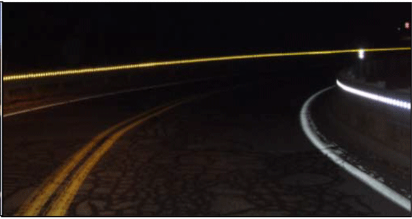 Photograph of a nighttime view of delineated concrete barriers. The delineated concrete barriers are installed on the inside and outside of the horizontal curve on a two-lane roadway.