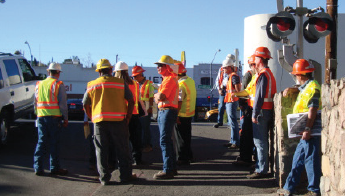 Diagnostic review team members wearing protective gear observe an at-grade crossing.