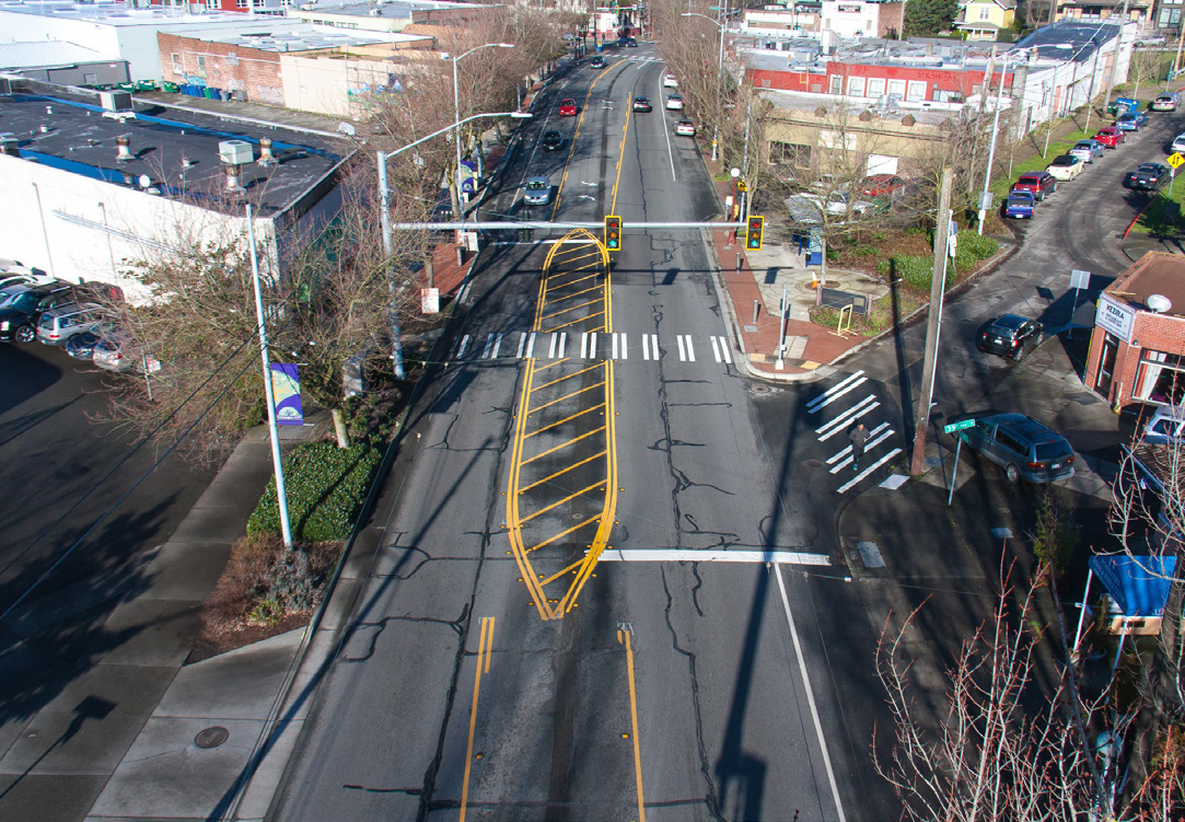 Photo shows the same road as Before, but with one lane heading in each direction, an extended median, extended curbs, and a two-way left turn lane.
