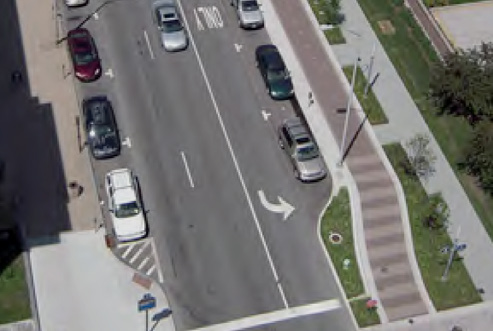 Photo shows a street with walkways and extended curbs between walkways and the road.