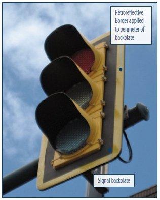 "Closeup photograph of a retroreflective traffic light, showing the signal backplate and the retroreflective border applied to the perimeter of the backplate"