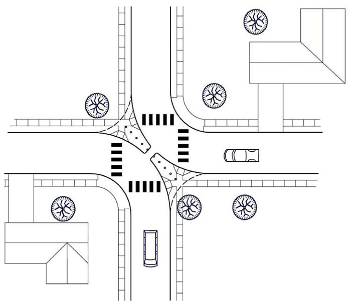 "Figure 3.21.1. Diagonal Diverter Schematic. This figure contains a schematic of a four leg intersection which has been turned into two two leg intersections by the placement of a diagonal diverter running from top left corner to bottom right corner of the intersection. The diverter consists of long, narrow curb extensions coming off of opposite facing corners. A channel between the two extensions would allow for bicycle traffic. The streets are lined by sidewalks. Houses occupy the top right and bottom left quadrant of the schematic. Vehicles can be seen in the bottom leg and right leg of the intersections."