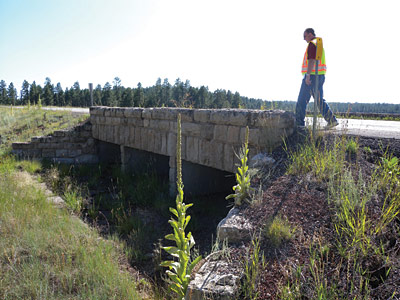 Page iii photo. A man in a safety vest is shown examining a headwall.