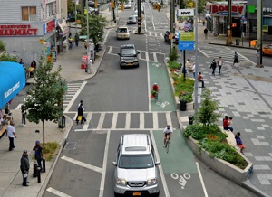 Road in NYC has a bike lane on the right marked for bicyclists, and crosswalks for pedestrians.