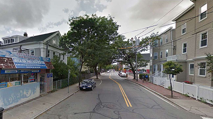 Figure 3.4.2. Lateral Shift with On-Street Parking. This figure contains a photograph of a downtown street using a lateral shift with on-street parking. A blue car is parked in front of a store in the left lane using on-street parking. The lanes shift from right to left without a median to allow for parking on the right hand side of the street near the lateral shift.