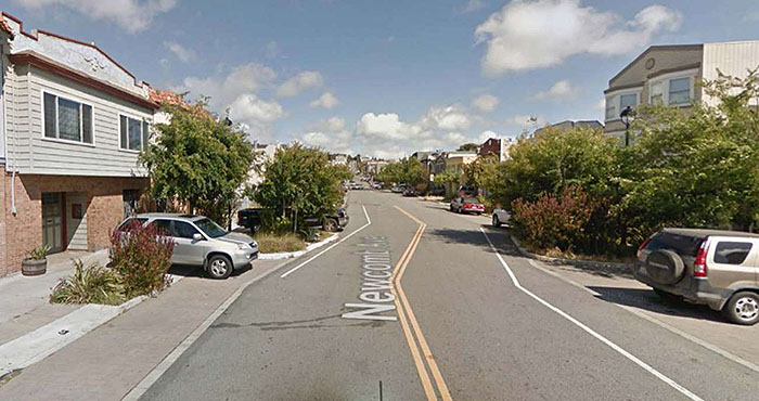 Figure 3.4.3. Midblock Lateral Shift. This figure contains a photograph of a street labeled Newcomb Ave.. Apartments and trees line either side of the two lane street and the lanes shift from left to right with a double yellow line and a midblock lateral shift.