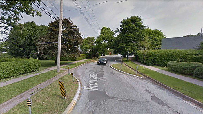 Figure 3.5.4. Chicane Designed to Retain Drainage Features. This figure contains a photograph of a chicane achieved using curb extensions. The street is labeled Romans Ave. and there is a truck driving towards the camera. Each curb extension has yellow and black reflectors following the curve of the extension and gutters have been left between the curb and the extension to allow for drainage