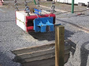 "A rectangular pendulum swinging mass representative of the weight of a 4,400 pound pickup truck. It is constructed of reinforced concrete and steel suspended by metal hooks and chains."