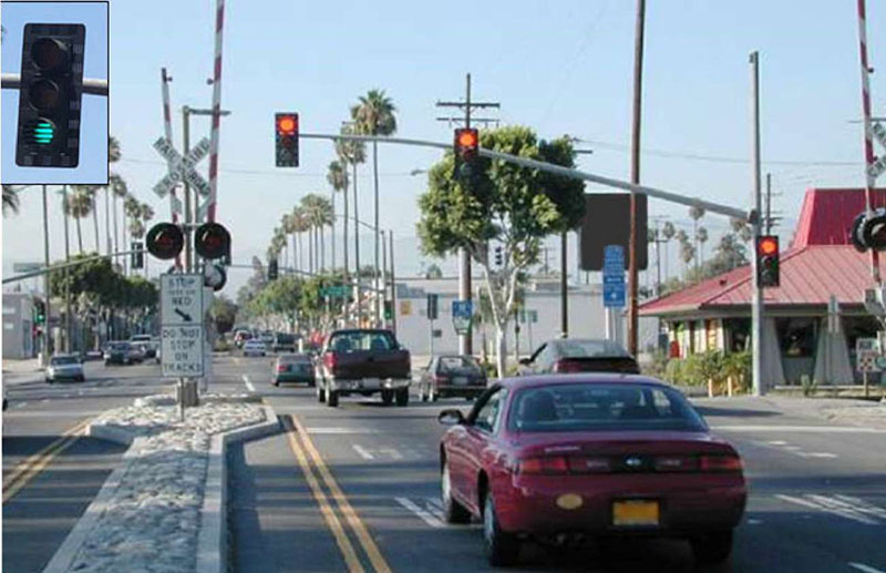 "Figure 41. Illustrative Example Showing Downstream Mounted Pre-Signal (SCAX Sierra Avenue Crossing at Orange Way, Fontana, CA, USDOT 026145L) - This figure is a photograph of a vehicle stopped at a red stop light before STOP HERE ON RED and DO NOT STOP ON TRACKS signs. There is no train approaching since the Crossing Gate's Flashing-Light Signals are not illuminated."