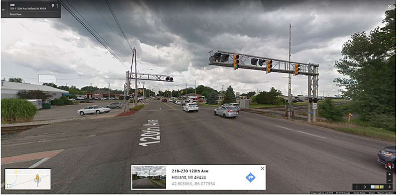 "Figure 42. Illustrative Example of a Cantilever-Mounted Pre-Signal (CSX 120th Avenue Crossing at E. Lakewood Boulevard in Holland, MI, USDOT 234648C) - This figure is a photograph of a pre-signal mounted on the railroad cantilever. There is another Crossing Gate and Cantilever on the other side of the road for the opposite traffic, but it does not have a pre-signal mounted on cantilever."