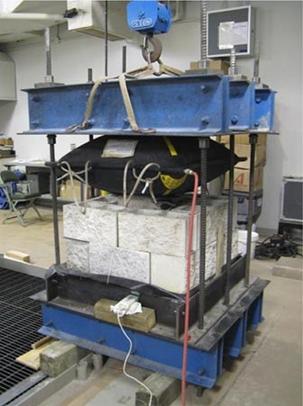 Figure 7. This is a photo showing a calibration reaction assembly with two courses of concrete masonry blocks stacked up and an inflated airbag pressed against them from the top.