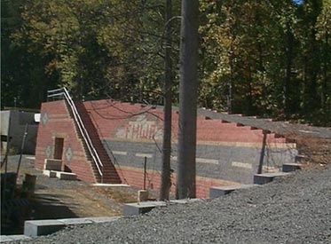 Figure 15. Long-range view of the FHWA prototype geosynthetic reinforced soil integrated bridge system. The facing modular block is decorative with FHWA inscribed and a road shown. A tunnel through the bridge and underneath a staircase is also depicted. 