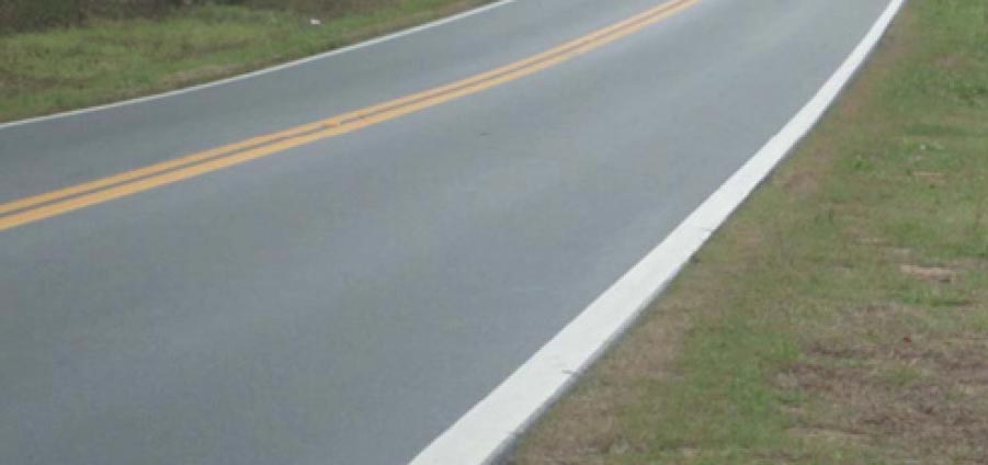 "A two-lane undivided roadway marked with a double yellow centerline and solid white edge line. The solid white edge line in the foreground of the image is visibility wider than the centerline markings."