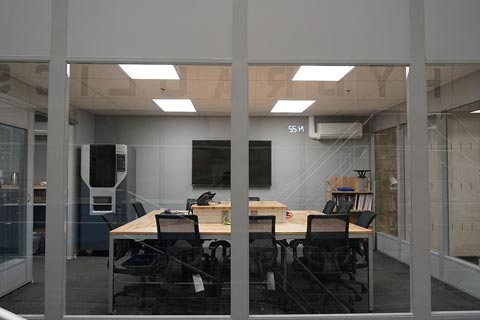 "the lab conference room with Fortus 3D printer in far-left corner."