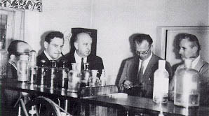 BPR officials on tour of Poland: H. A. Radzikowski (third from left), S. E. Farin (looking down) and R. S. Anderson (right). Photo and the following caption were taken from their 1959 report: "Another view of American and Polish engi- neers inspecting highway testing laboratory. Note the feminine touch with cur- tains on the windows. Flowers were also seen on desks. There is a trend to employ more girl technicians in the laboratories. We were told by the Polish engineers that their experience is that girls are more thorough in this type of repetitive and detail tests."