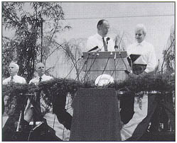 Administrator Thomas D. Larson and Governor Rose Mofford at podium during opening ceremony for I-10, the Papago Freeway, in Phoenix, AZ. Seated are Senators Dennis DeConcini (left) and John McCain.