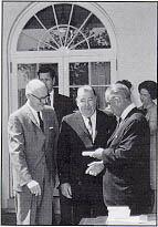 After signing the Highway Safety Act of 1966, President Lyndon Johnson talks with Representative George H. Fallon (MD), Chairman, House Committee on Public Works (left), and Senator Jenning Randolph (WV), Chairman, Subcommittee on Public Roads.