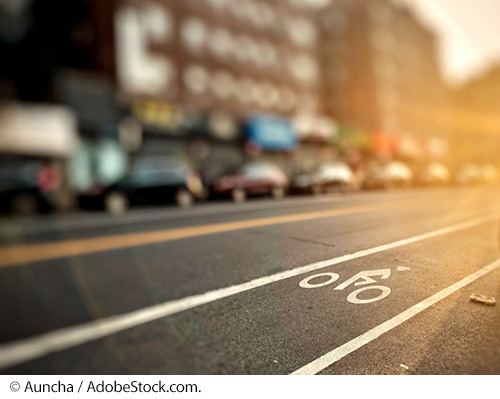 A city street with a designated bicycle lane seen at sunset. Image Source: © Auncha / AdobeStock.com.